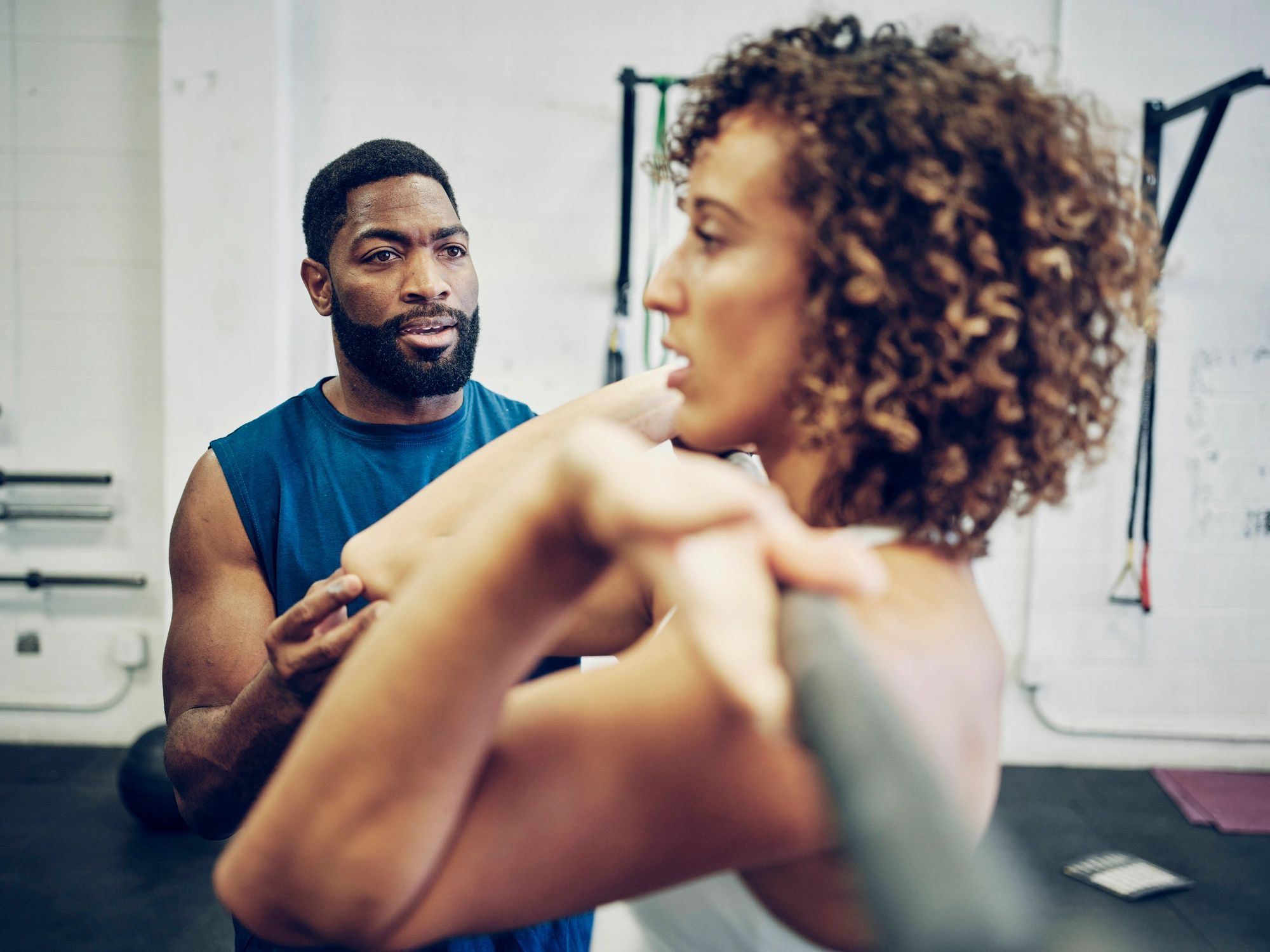 Trainer instructing a woman during a cross training exercise in a gym