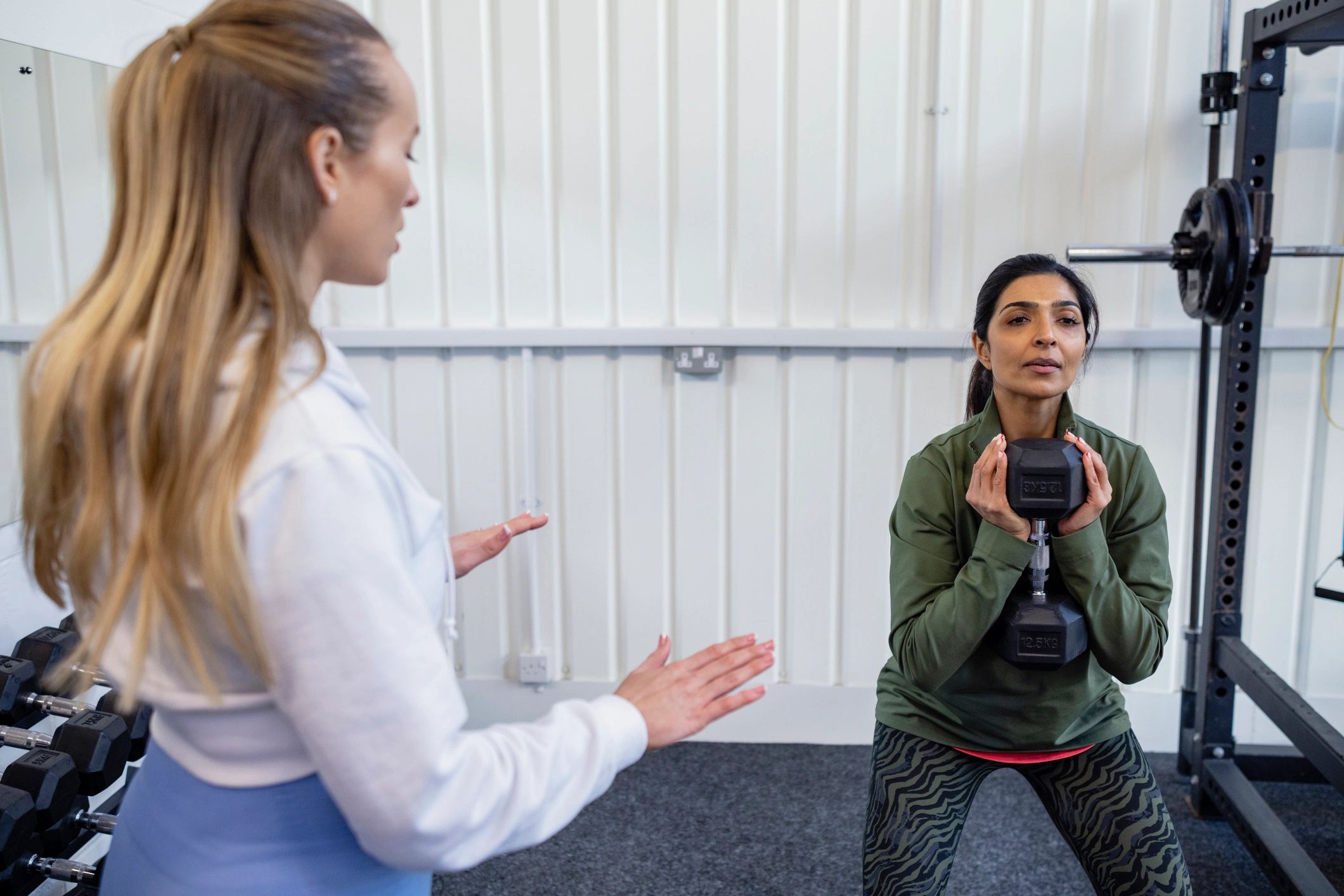 Trainer coaching a client doing weighted squats