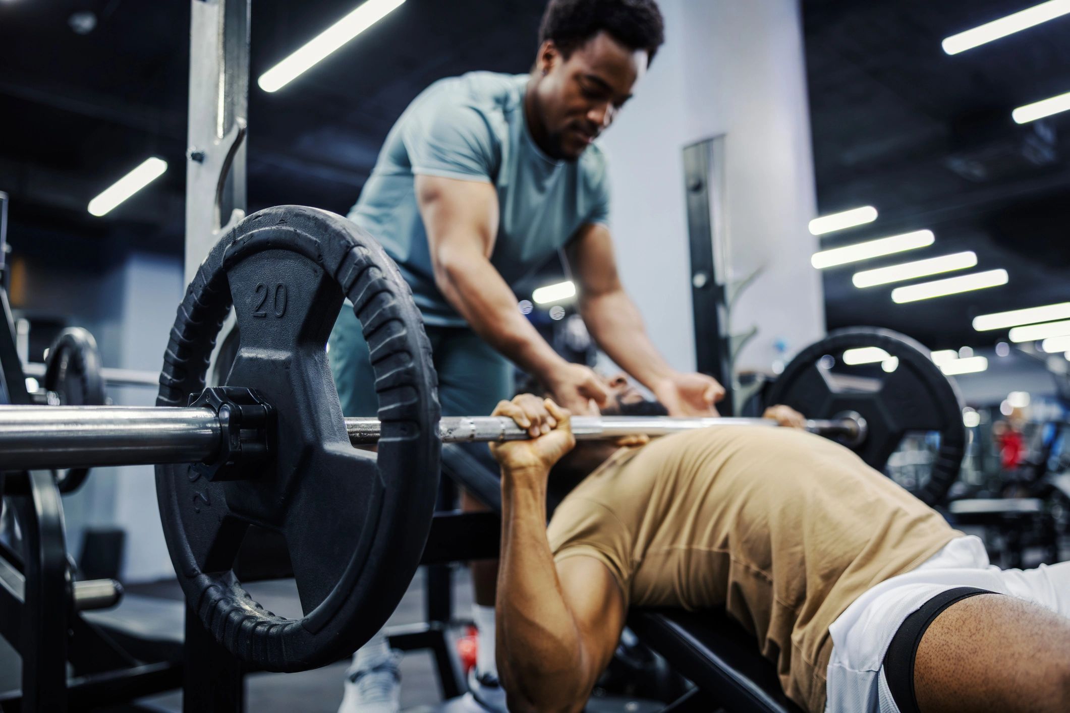 Personal trainer spotting a client bench pressing in a gym